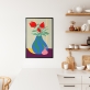 Poster de um vaso azul com detalhes verdes e uma pêra na frente, numa superfície roxa e uma parede com listras verticais em tons de azul e amarelo. Dentro do vaso, há três tulipas vermelhas com folhas verdes. 1